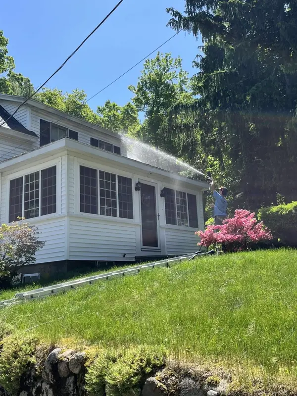 Roof wash in progress on a white home